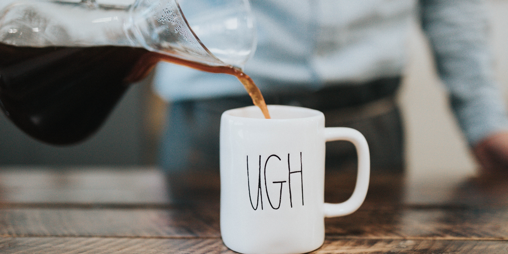 Woman pouring coffee into a mug with the word 